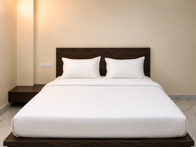 A made-up double bed against a sage green wall