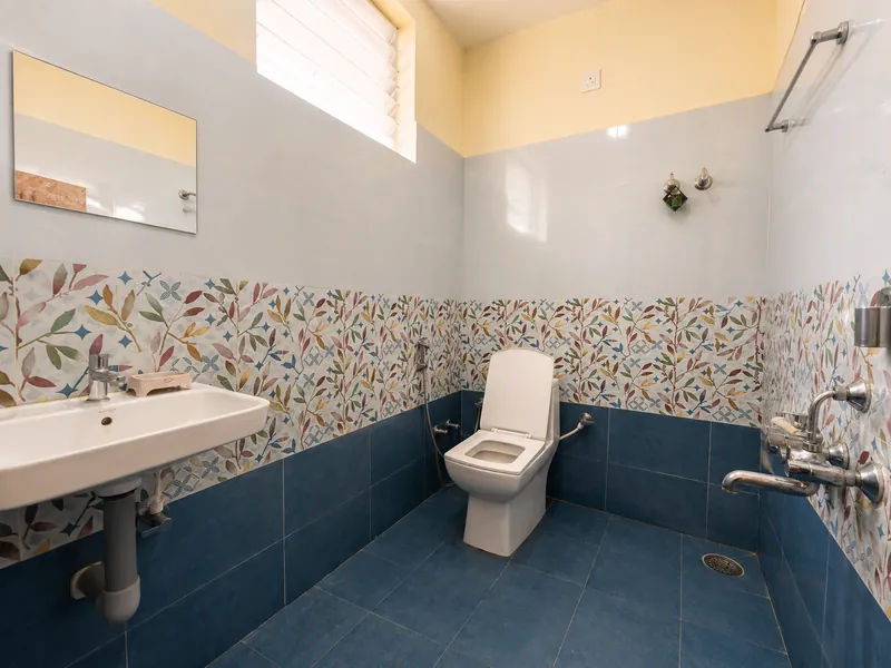 Attached bathroom finished in blue tile with an overhead shower